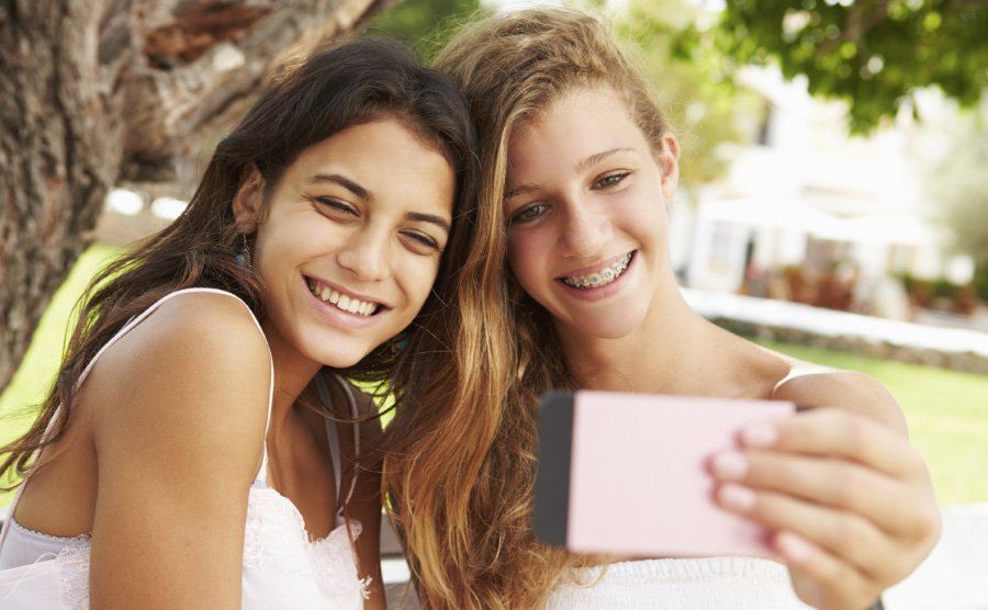 Two teens smiling after seeing orthodontist in Ludlow